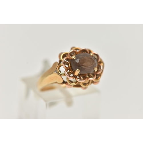 211 - A YELLOW METAL SMOKY QUARTZ RING, set with an oval cut smoky quartz, in a four claw open work settin... 