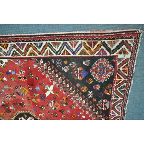 1299 - A WOOLLEN RED GROUND RUG, with a repeating pattern of birds, three central medallions, black filled ... 