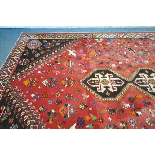 1299 - A WOOLLEN RED GROUND RUG, with a repeating pattern of birds, three central medallions, black filled ... 