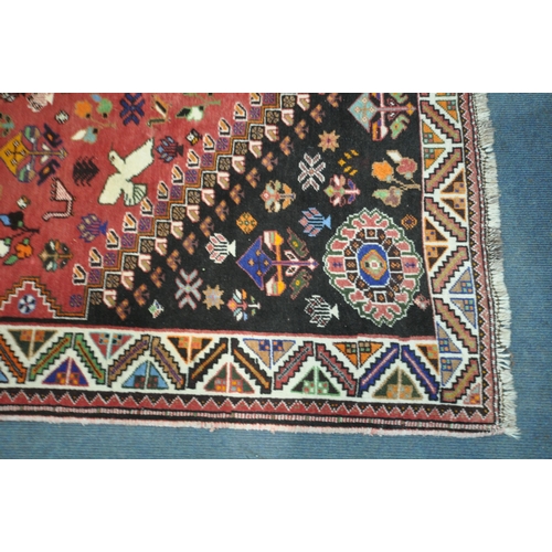 1299 - A WOOLLEN RED GROUND RUG, with a repeating pattern of birds, three central medallions, black filled ... 