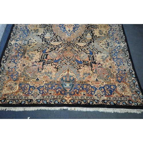 1300 - A LARGE WOOLLEN CREAM GROUND RUG, with a repeating foliate pattern, within a dark blue field, and a ... 