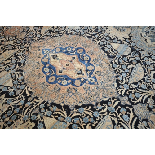 1300 - A LARGE WOOLLEN CREAM GROUND RUG, with a repeating foliate pattern, within a dark blue field, and a ... 