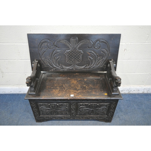 1308 - AN EARLY TO MID 20TH CENTURY DARK OAK MONKS BENCH, with lion armrests, flanking a hinged storage com... 