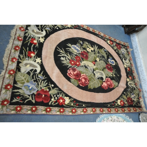 1335 - A WOOLLEN FLORAL RUG, on a black ground, 248cm x 168cm, along with a Chinese blue circular rug, and ... 