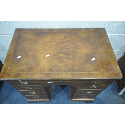 1340 - A REPRODUCTION GEORGIAN STYLE WALNUT KNEE HOLE DESK, the quarter veneer top, over an arrangement of ... 