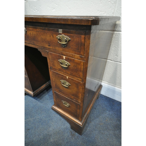 1340 - A REPRODUCTION GEORGIAN STYLE WALNUT KNEE HOLE DESK, the quarter veneer top, over an arrangement of ... 