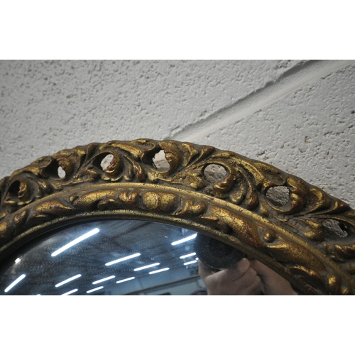 1401 - A CIRCULAR GILT FRAMED CONVEX WALL MIRROR, diameter 52cm, along with a carved oak barometer (conditi... 