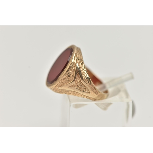 24 - A 9CT GOLD SIGNET RING, designed as an oval carnelian panel within a tapered ring mount with texture... 