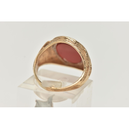 24 - A 9CT GOLD SIGNET RING, designed as an oval carnelian panel within a tapered ring mount with texture... 