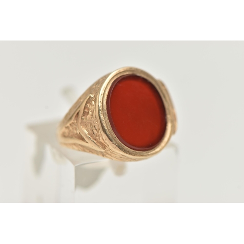 24 - A 9CT GOLD SIGNET RING, designed as an oval carnelian panel within a tapered ring mount with texture... 