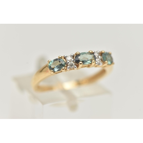 36 - A 14CT GEMSTONE RING, designed as three oval cut green gems, assessed as topaz, interspaced by a tot... 