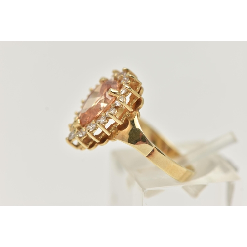 39 - A DRESS RING, designed as a central pear shape peach cubic zirconia within a colourless circular cub... 