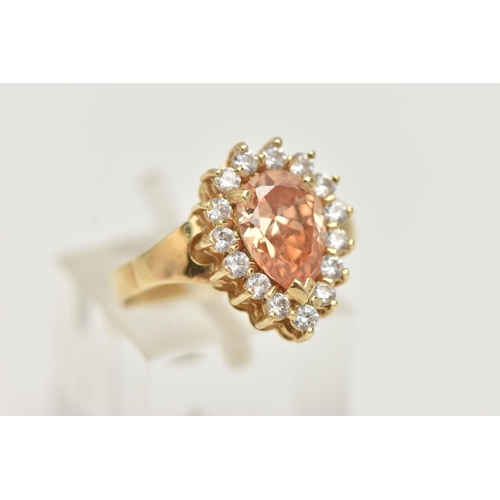 39 - A DRESS RING, designed as a central pear shape peach cubic zirconia within a colourless circular cub... 