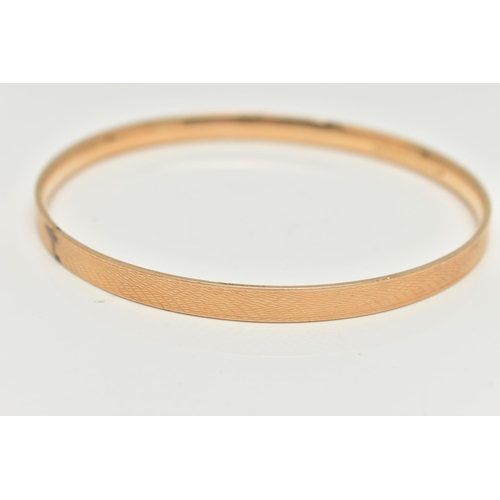 127 - A 9CT GOLD METAL CORE BANGLE, engine turned pattern, stamped '9ct gold solid metal core', approximat... 