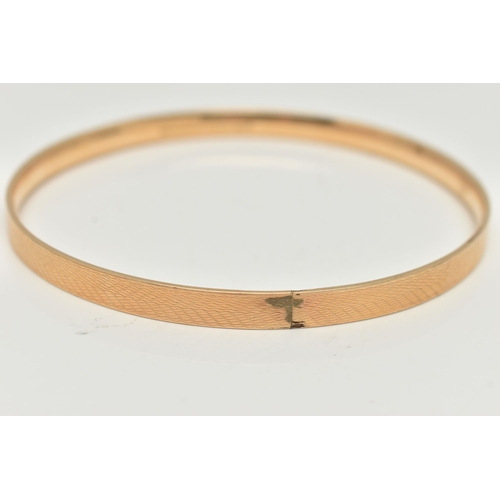 127 - A 9CT GOLD METAL CORE BANGLE, engine turned pattern, stamped '9ct gold solid metal core', approximat... 