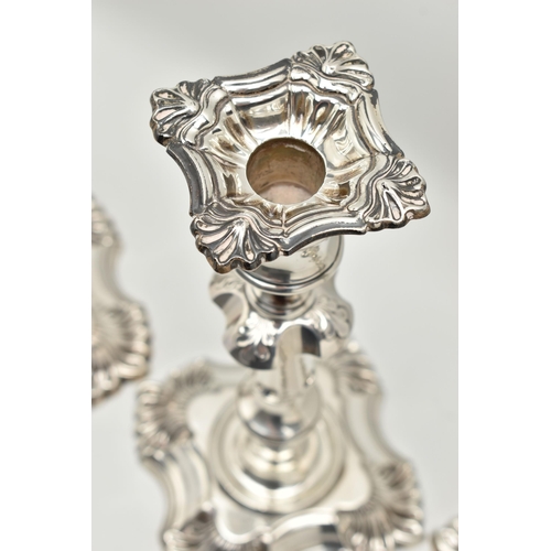 193 - A GEORGE V SILVER SET OF FOUR CANDLESTICKS  IN GEORGE II STYLE, with removable shaped square drip pa... 