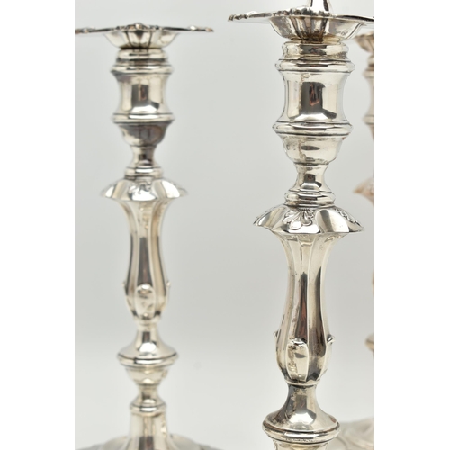 193 - A GEORGE V SILVER SET OF FOUR CANDLESTICKS  IN GEORGE II STYLE, with removable shaped square drip pa... 