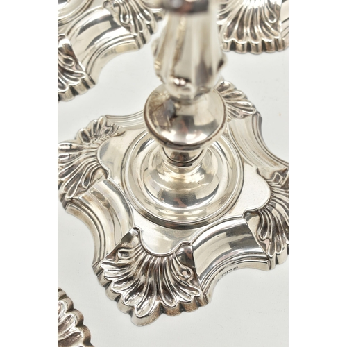 193 - A GEORGE V SILVER SET OF FOUR CANDLESTICKS  IN GEORGE II STYLE, with removable shaped square drip pa... 