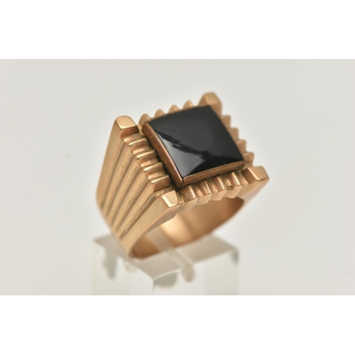 28 - A LARGE YELLOW METAL GENTS RING, square form ring inlay set with onyx, approximate width 19mm, unmar... 