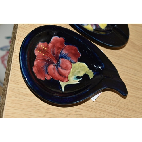 474 - TWO MOORCROFT POTTERY 'HIBISCUS' PATTERN ASHTRAYS, one of teardrop shape, tube lined with a pink/pur... 