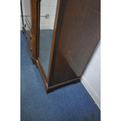 1243 - A REPRODUCTION MAHOGANY COMPACTUM WARDROBE, fitted with double bevelled mirrored doors, flanking a s... 