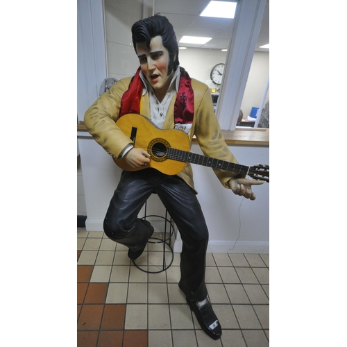 1358 - A LIFESIZE FIGURE OF THE WORLD FAMOUS ROCK AND ROLL STAR ELVIS PRESLEY, seated on a stool, playing a... 