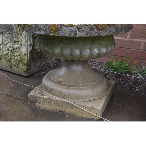 1005 - A PAIR OF LOW WEATHERED COMPOSITE CAMPAGNA GARDEN URNS, on a square base, diameter 57cm x height 46c... 