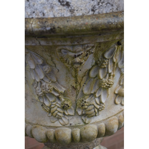 1007 - A WEATHERED COMPOSITE GARDEN URN, depicting masks and flowers with swag, on an odd Reeded cylindrica... 