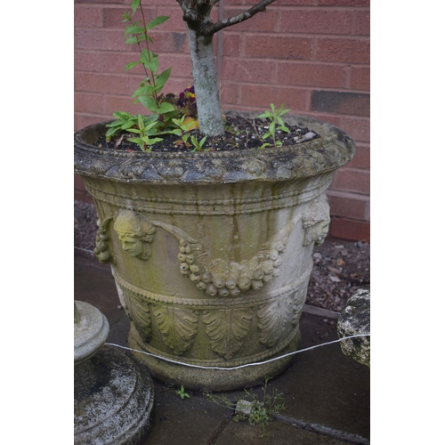 1008 - A WEATHERED COMPOSITE CIRCULAR PLANTER, with female masks, joined swags and grapes, containing a pla... 