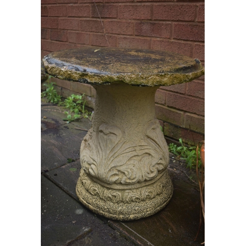 1023 - A CREAM COMPOSITE GARDEN TABLE, on a separate foliate base, diameter 51cm, along with a grey composi... 