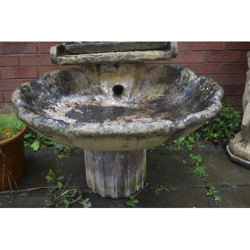 1025 - A WEATHERED CREAM COMPOSITE SHELL SHAPED BIRD BATH, the top with later figures of three clad ladies,... 