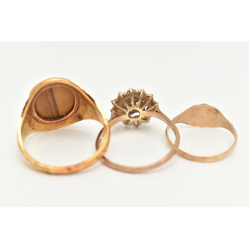 14 - THREE 9CT GOLD RINGS, to include a textured signet ring set with an oval tiger's eye panel, a furthe... 