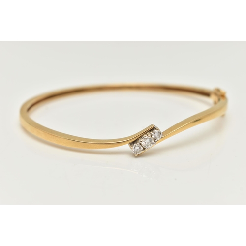 22 - AN 18CT GOLD DIAMOND HINGED BANGLE, a polished bangle of cross over design, set with three round bri... 