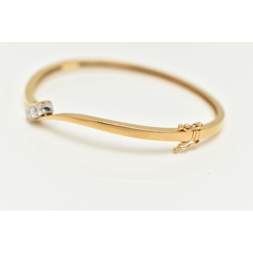 22 - AN 18CT GOLD DIAMOND HINGED BANGLE, a polished bangle of cross over design, set with three round bri... 