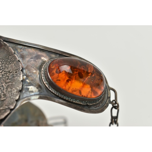 33 - A LARGE WHITE METAL AND COPAL AMBER BRACELET, designed as a horse saddle, fitted with chain stirrups... 