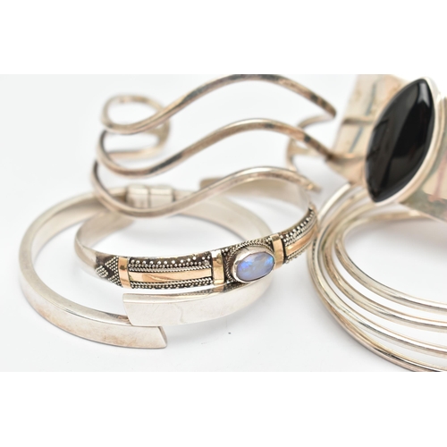 46 - FIVE WHITE METAL BANGLES, the first a wide white metal cuff bangle, set with a navette cabochon onyx... 