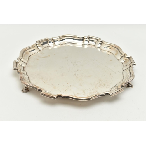 101 - A GEORGE V SILVER SHAPED CIRCULAR SALVER, pie crust edge, plain centre, on three hoof feet, stamped ... 