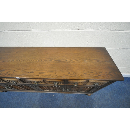 1254 - A 20TH CENTURY OAK SIDEBOARD, fitted with four drawers, above four linenfold cupboard doors, raised ... 