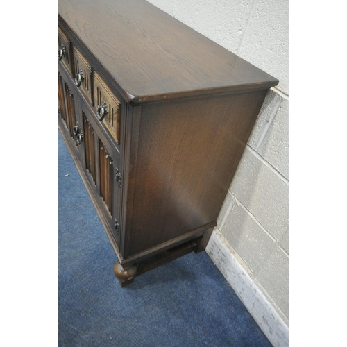 1254 - A 20TH CENTURY OAK SIDEBOARD, fitted with four drawers, above four linenfold cupboard doors, raised ... 