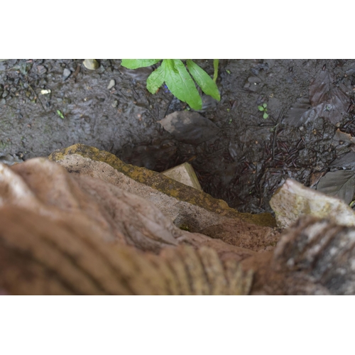 1010 - A WEATHERED COMPOSITE GARDEN WATER FEATURE, of a lady sitting on rocks within a shell, holding a she... 