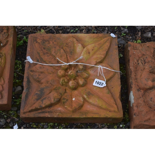 1022 - THREE WEATHERED COMPOSITE TILES, each with a different pattern of a flower head, 30cm squared (condi... 