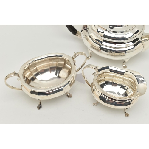 79 - A GEORGE V SILVER THREE PIECE TEA SET, of a faceted design, comprising of a teapot fitted with an eb... 