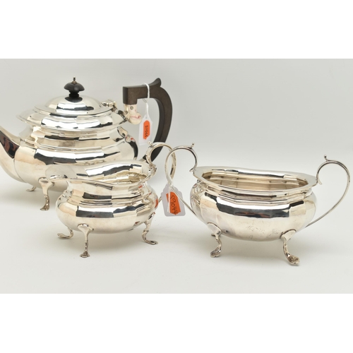 79 - A GEORGE V SILVER THREE PIECE TEA SET, of a faceted design, comprising of a teapot fitted with an eb... 