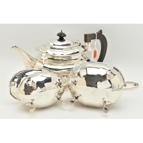 79 - A GEORGE V SILVER THREE PIECE TEA SET, of a faceted design, comprising of a teapot fitted with an eb... 