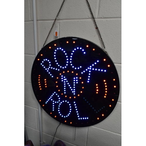 531 - A CIRCULAR BLACK WALL HANGING ILLUMINATING LED SIGN 'ROCK N ROLL', hanging on a metal chain, diamete... 