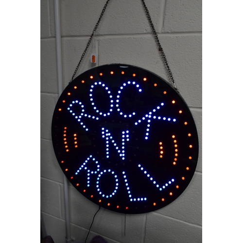 531 - A CIRCULAR BLACK WALL HANGING ILLUMINATING LED SIGN 'ROCK N ROLL', hanging on a metal chain, diamete... 