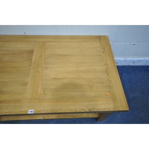 1263 - A SOLID OAK RECTANGULAR COFFEE TABLE, with a double sided drawer, raised on block legs, united by an... 