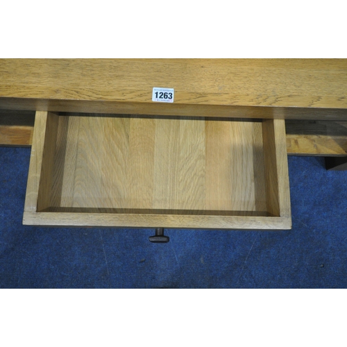 1263 - A SOLID OAK RECTANGULAR COFFEE TABLE, with a double sided drawer, raised on block legs, united by an... 