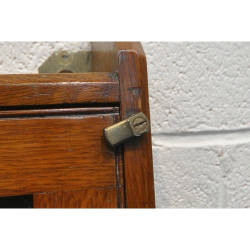 1309 - AN OAK WALL HANGING COLLECTORS CABINET, with a fall front glazed door, that's enclosing two shelves ... 