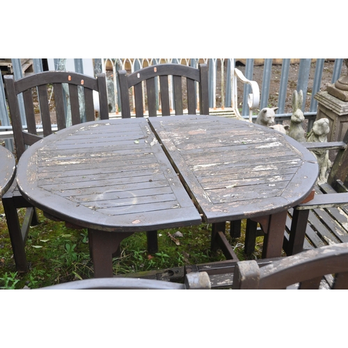 1017 - A STAINED TEAK OVAL EXTENDING GARDEN TABLE, a smaller circular folding table, a set of four chairs a... 